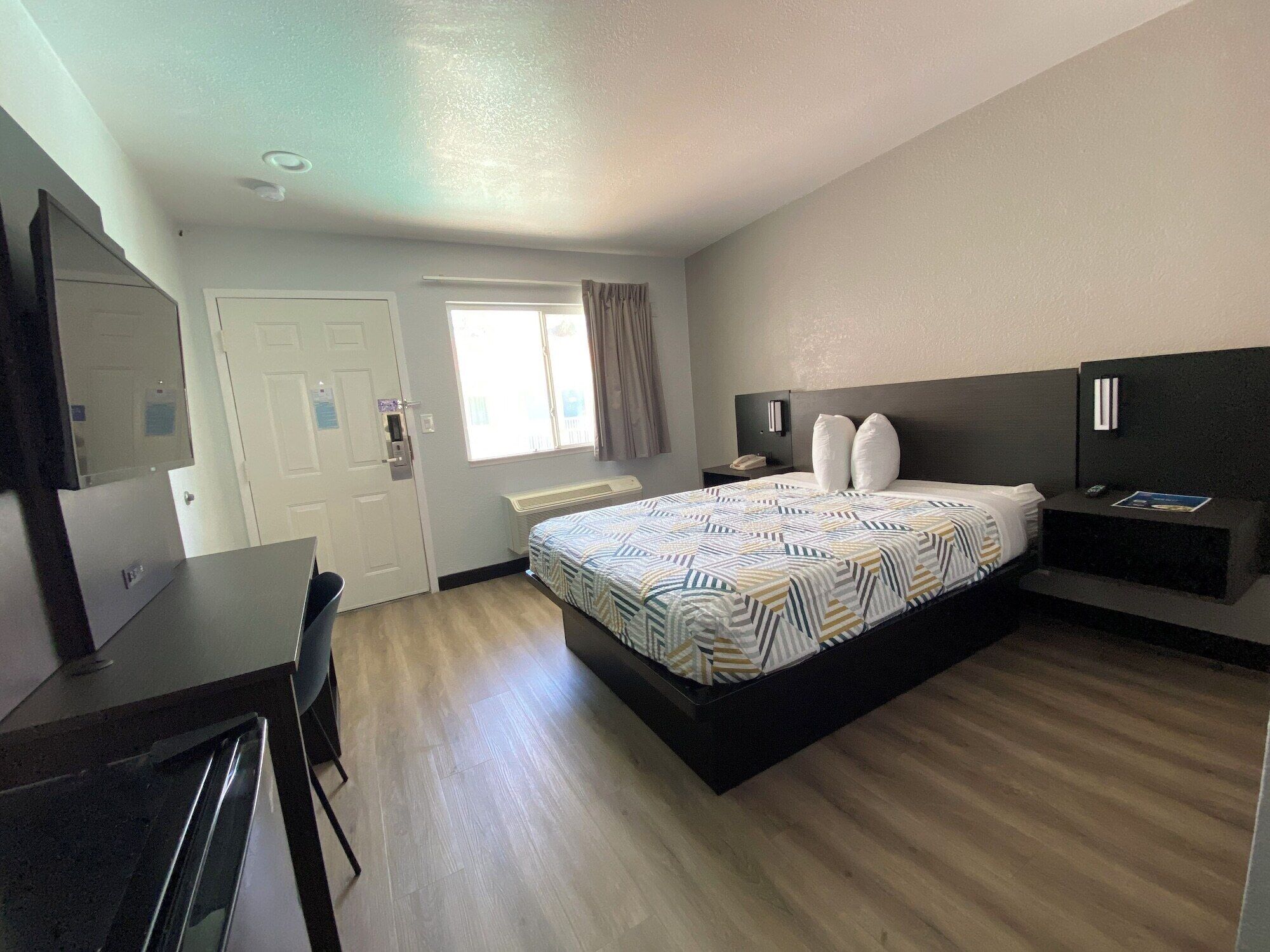 Una habitación de hotel con cama, mesita de noche y escritorio con silla.