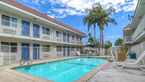 Un hotel con piscina, varios balcones y palmeras.