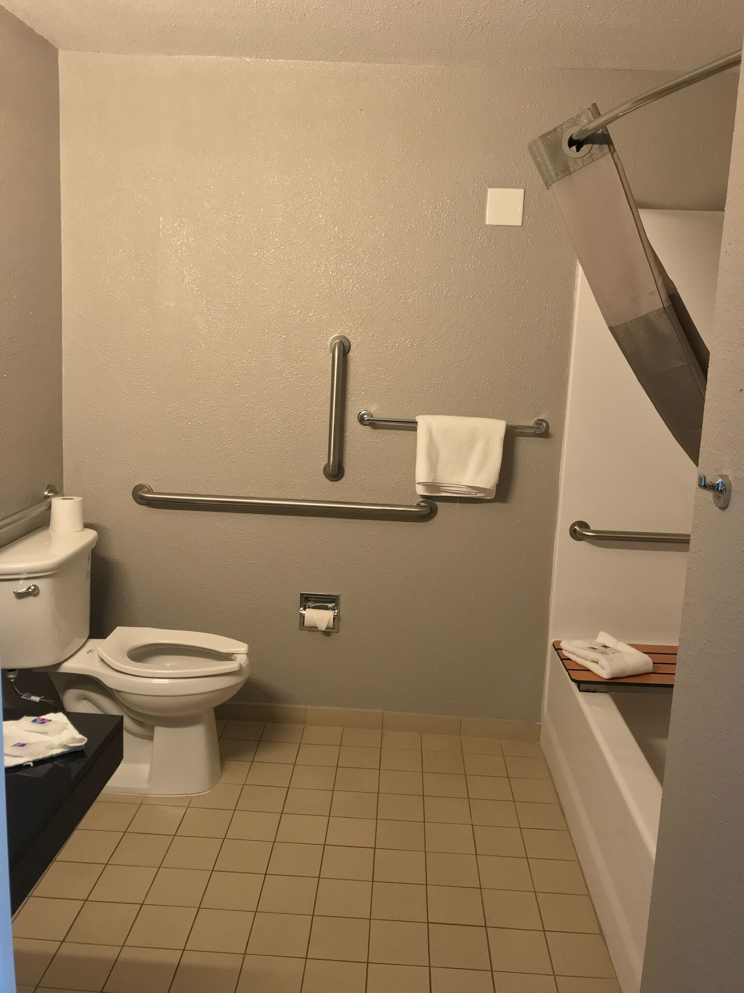 Un bany petit amb vàter, un lavabo, una barra de tovalloles i una barana.