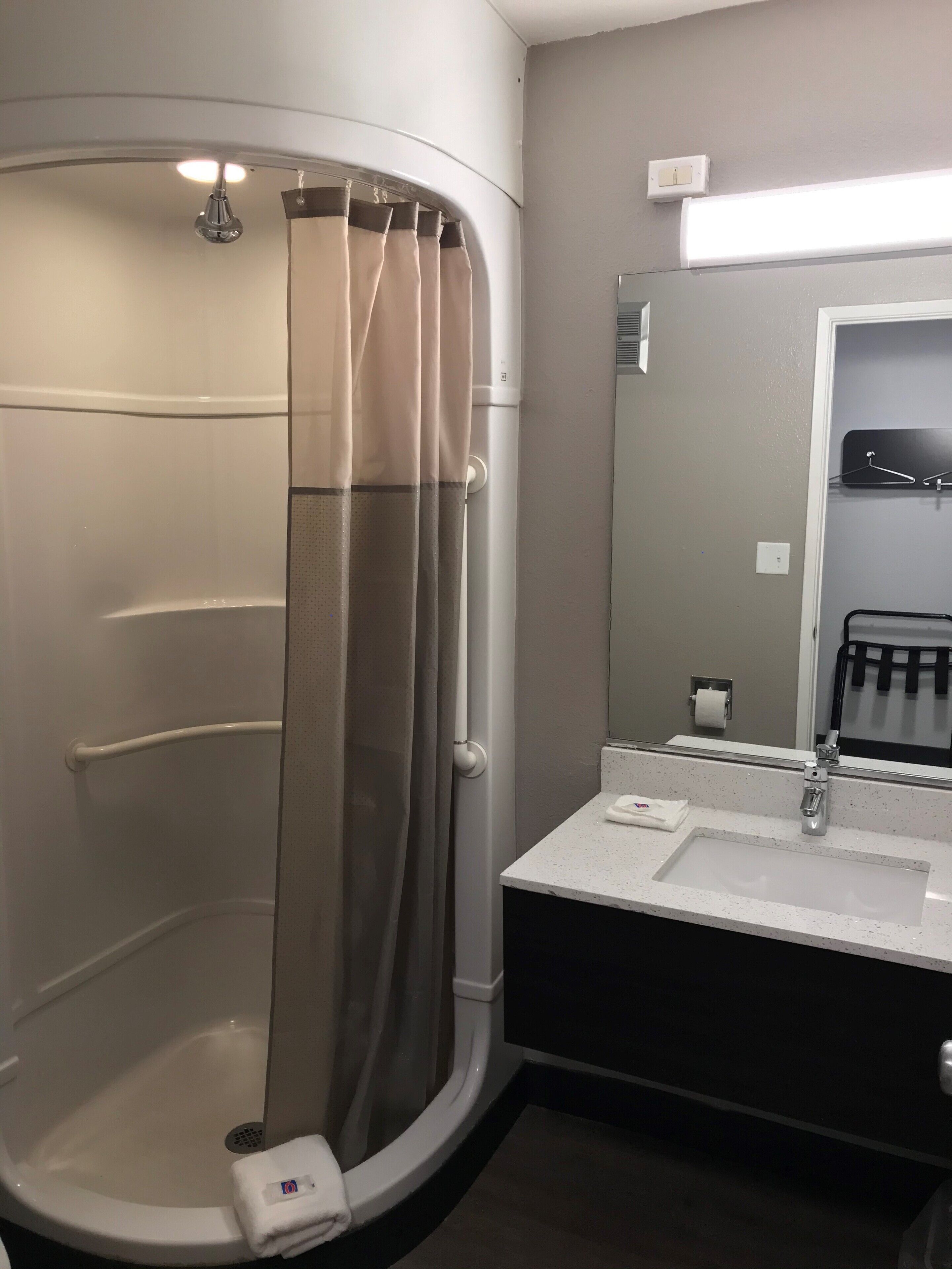 A modern bathroom with a walk-in shower, a sink, and a mirror.