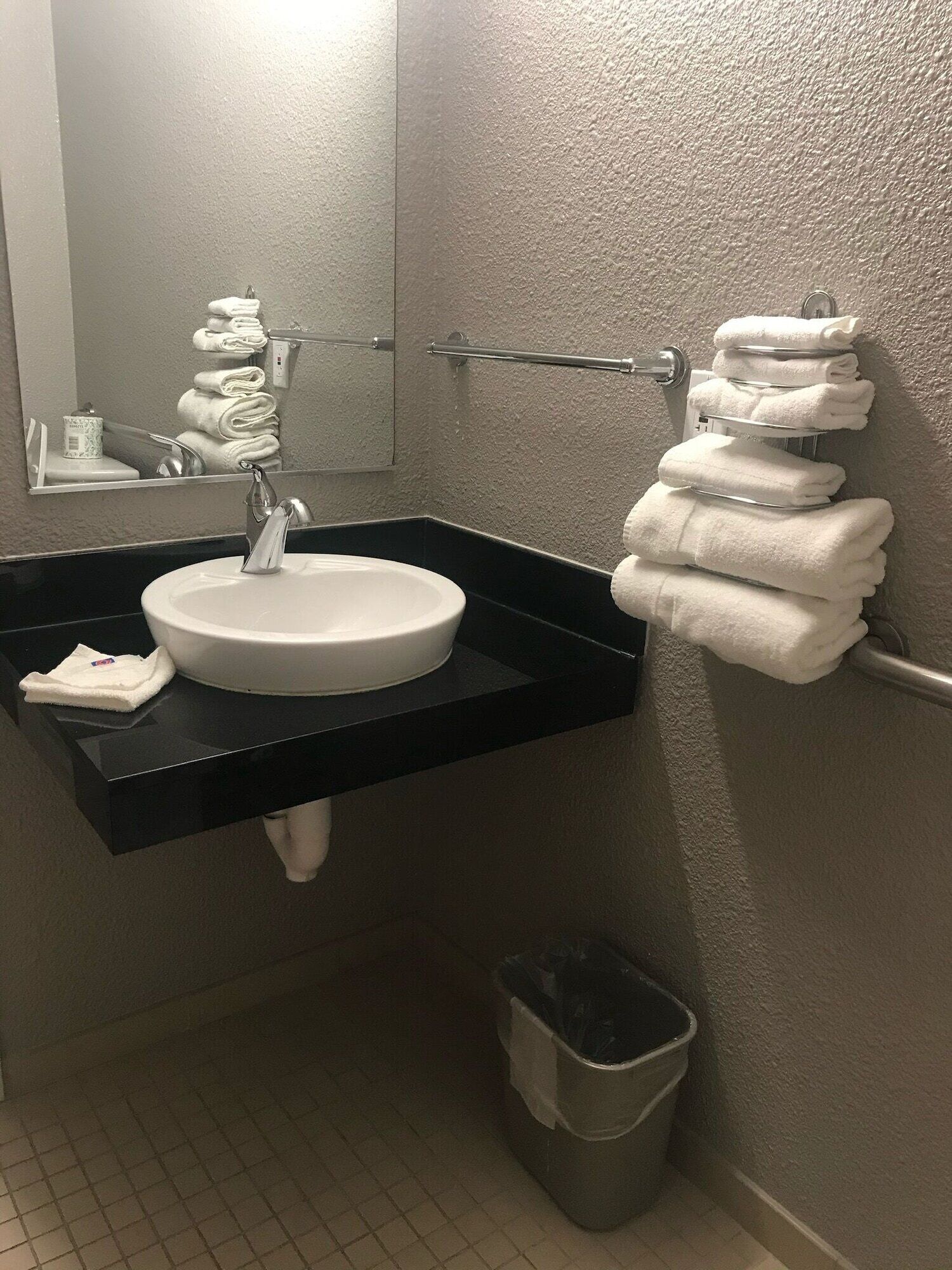 A bathroom with a round sink, a towel rack, and a trash bin.