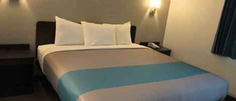 Una habitación de hotel con una cama, dos mesitas de noche y dos lámparas de pared.