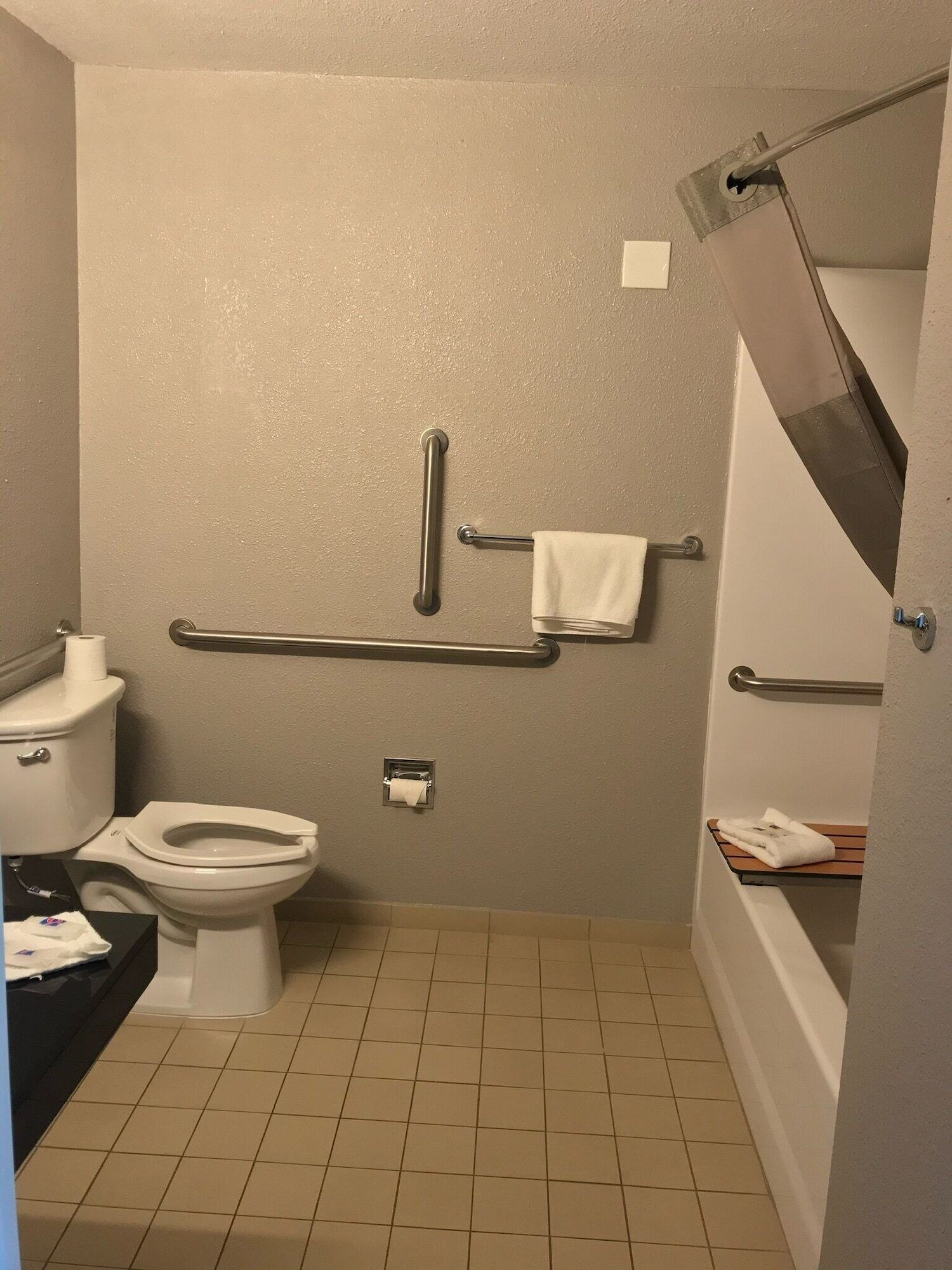 Une salle de bain équipée de toilettes, d’un bidet, d’un porte-serviettes et de barres d’appui.
