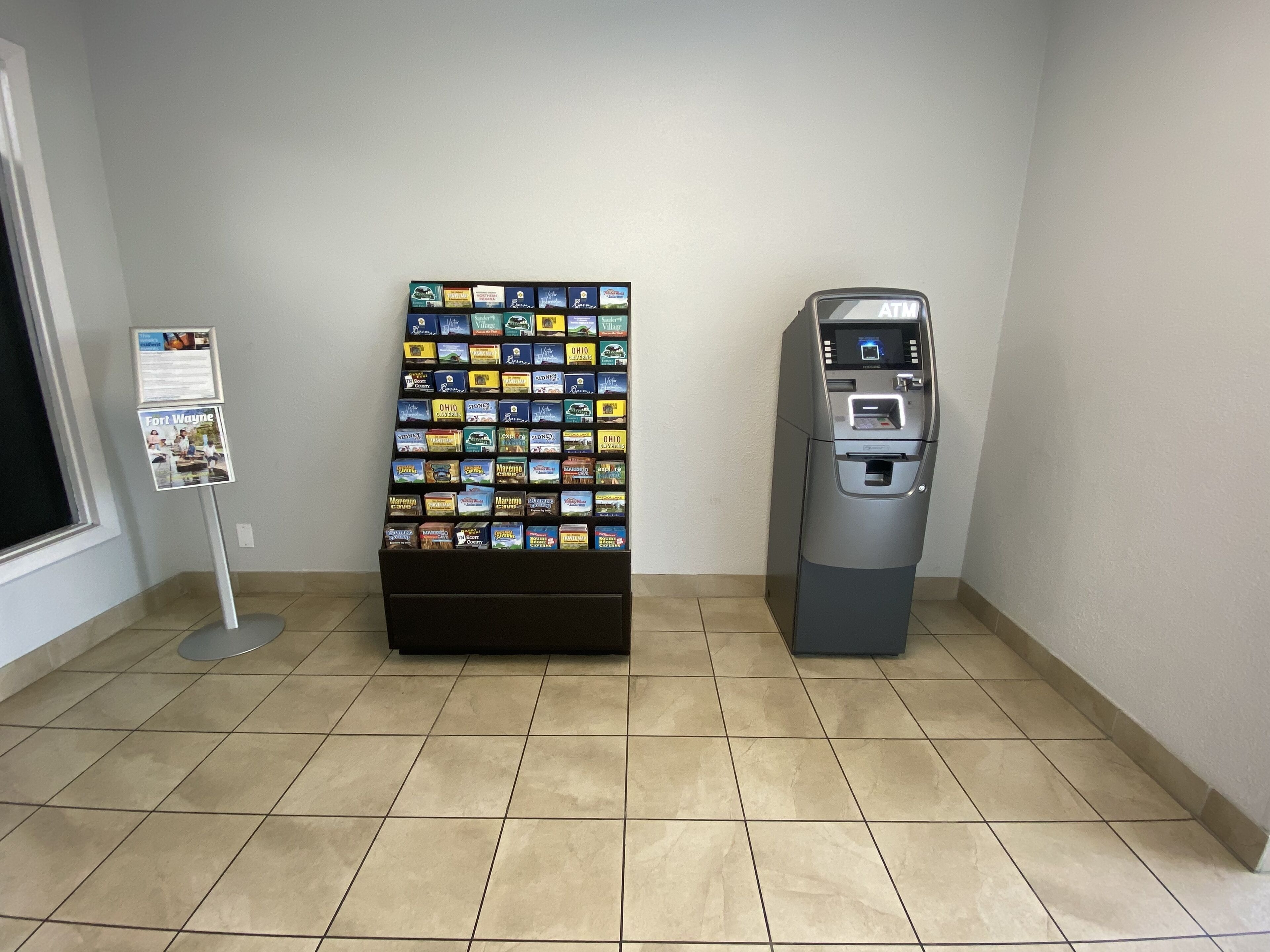 A vending machine and a display of snack boxes in a room with tiled flooring.