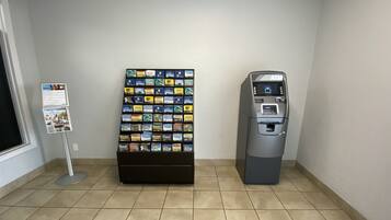 A vending machine and a display of snack boxes in a room with tiled flooring.