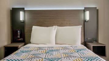 A hotel room with a bed, two bedside tables, a wall-mounted light fixture, and a telephone.