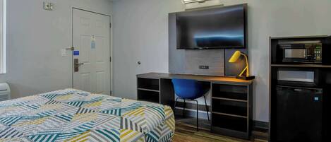 Une chambre d’hôtel équipée d’un lit, d’un bureau avec une chaise, d’une télévision et d’un four à micro-ondes.