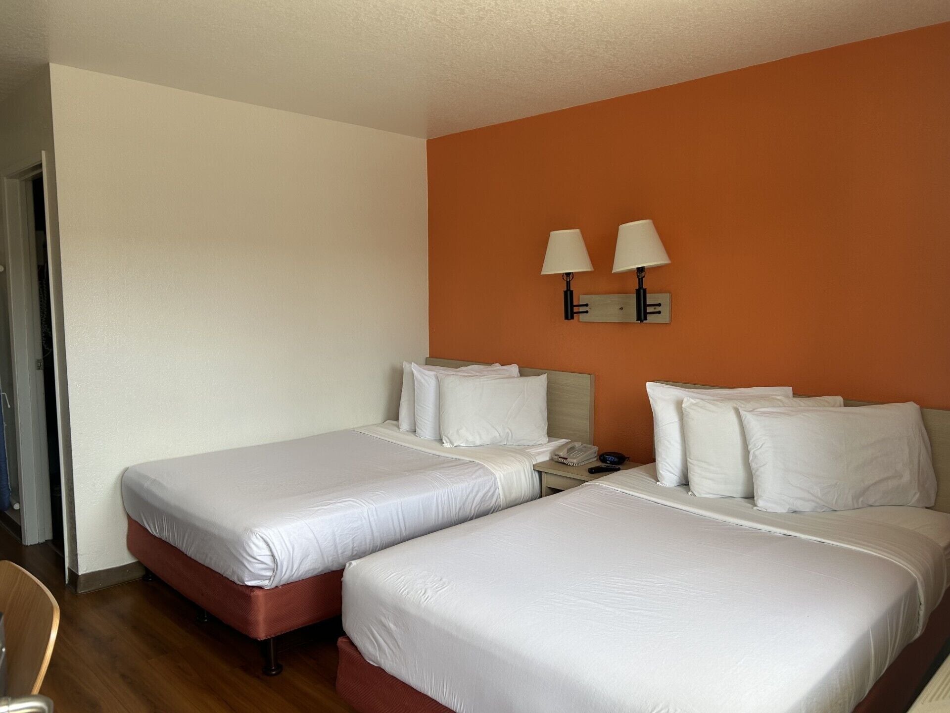 A hotel room with two beds, a nightstand, a lamp, and a telephone.