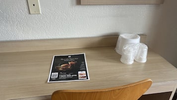 Un mostrador de hotel con un menú, una silla y una ventana que da a una valla blanca.
