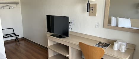 Une chambre d’hôtel avec un bureau en bois, une télévision, une lampe, une chaise et un lit.