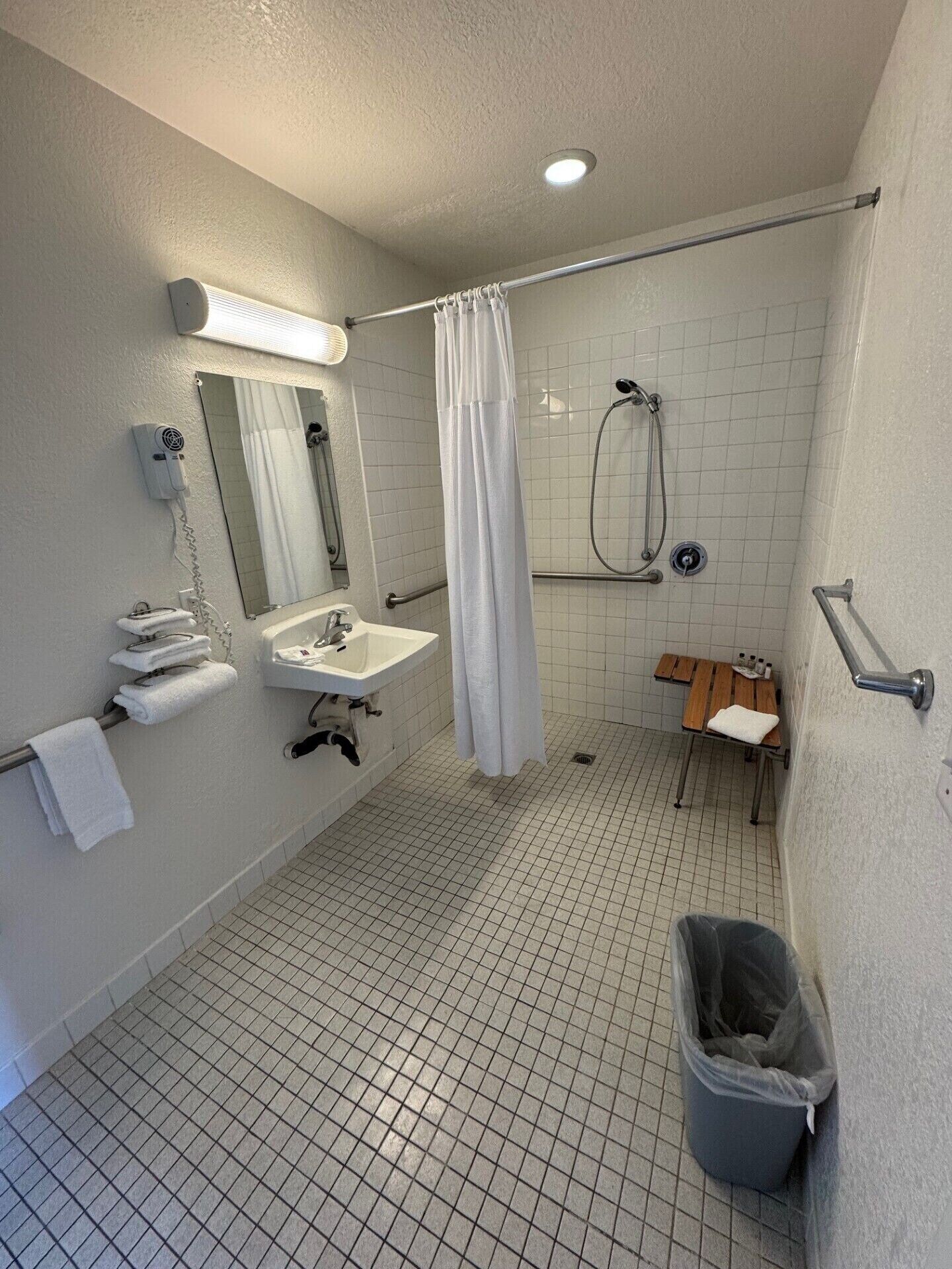 A bathroom with a shower, sink, and toilet.