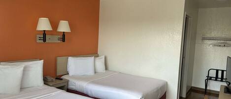 Habitación de hotel con dos camas, una mesita de noche y dos lámparas de pared.