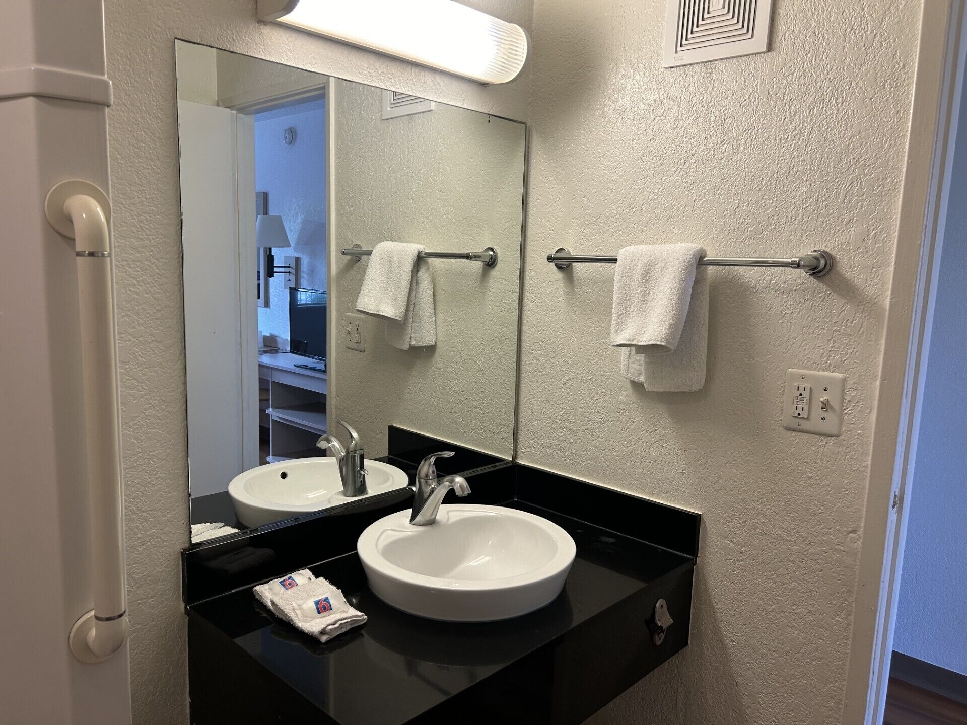 Ein Badezimmer mit zwei Waschbecken, einem Spiegel und einem Handtuchhalter.