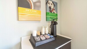 A coffee station with disposable cups, a coffee maker, and a tray of snacks. - Motel 6 Del Rio, TX (Del Rio)