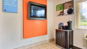 A hotel lobby with a digital display, a coffee station, and a sign about the Denver active tornado season.