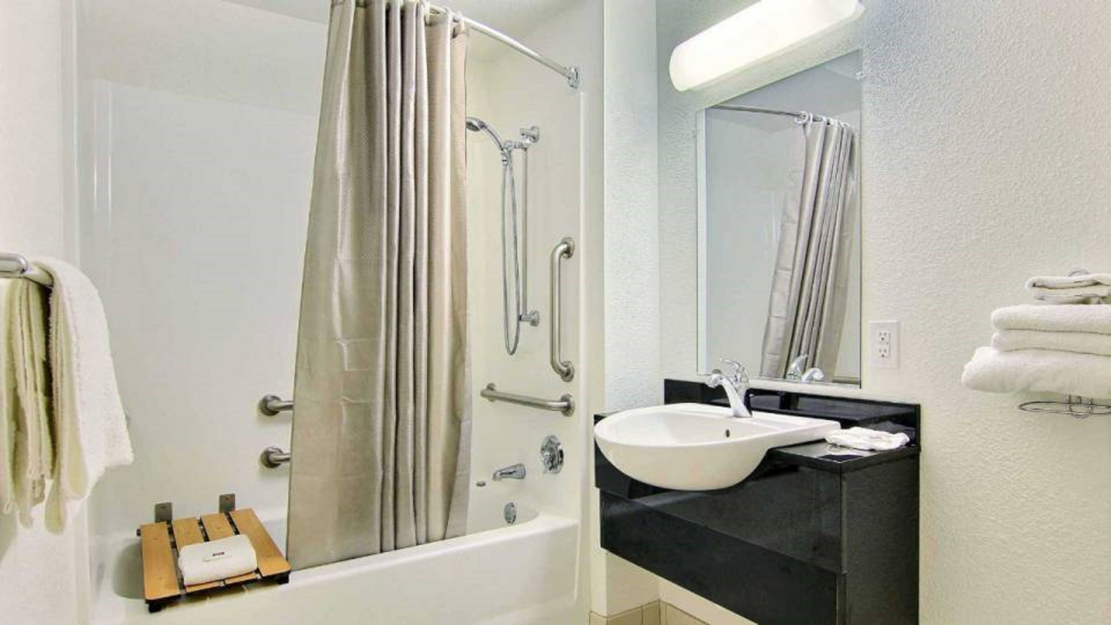 Un baño con bañera, ducha, lavamanos y espejo.