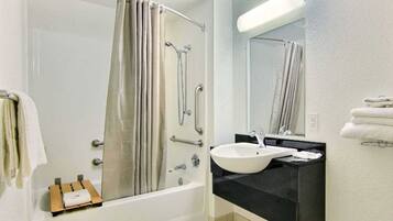 Un baño con bañera, ducha, lavamanos y espejo.