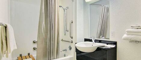 Un baño con bañera, ducha, lavamanos y espejo.