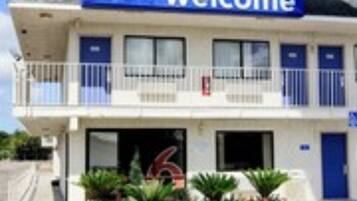 Ein Motel mit einem 'Welcome'-Schild, einem Balkon und der Nummer 6.