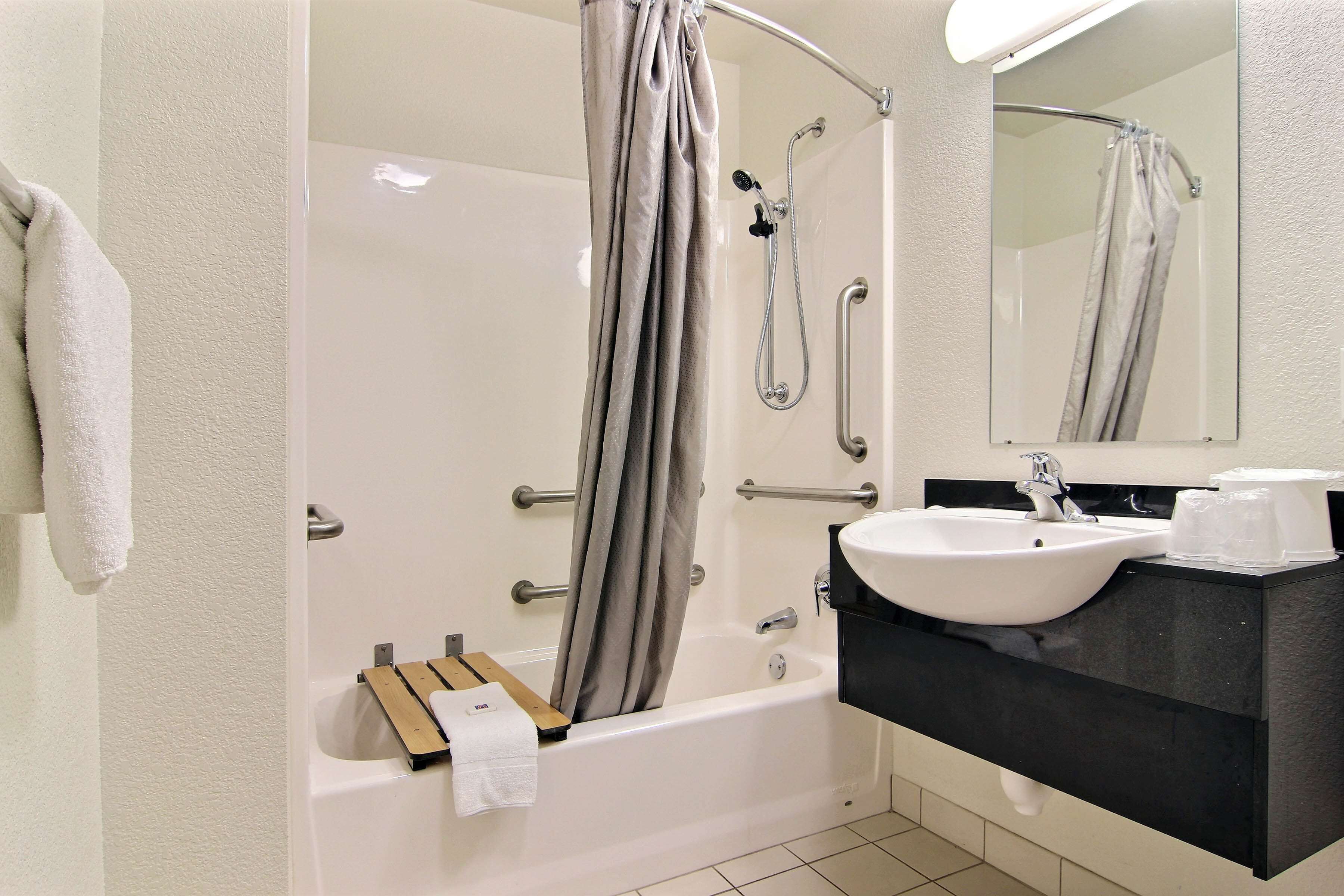 A bathroom with a bathtub, a sink, a mirror, and a towel rack.