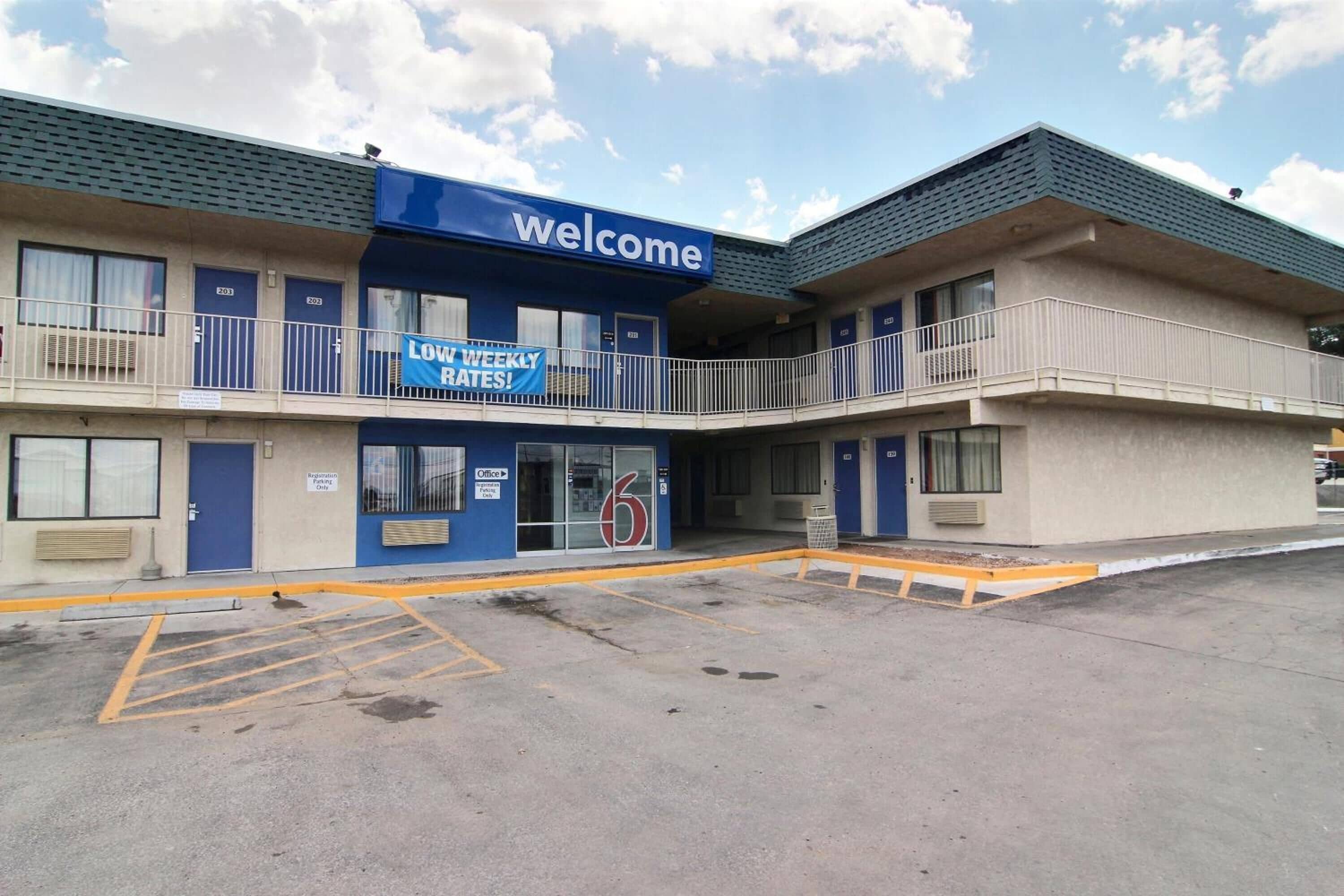 Un edificio de dos pisos con un cartel de 'Welcome' y un banderín que anuncia 'Tarifas Semanales Bajas'.