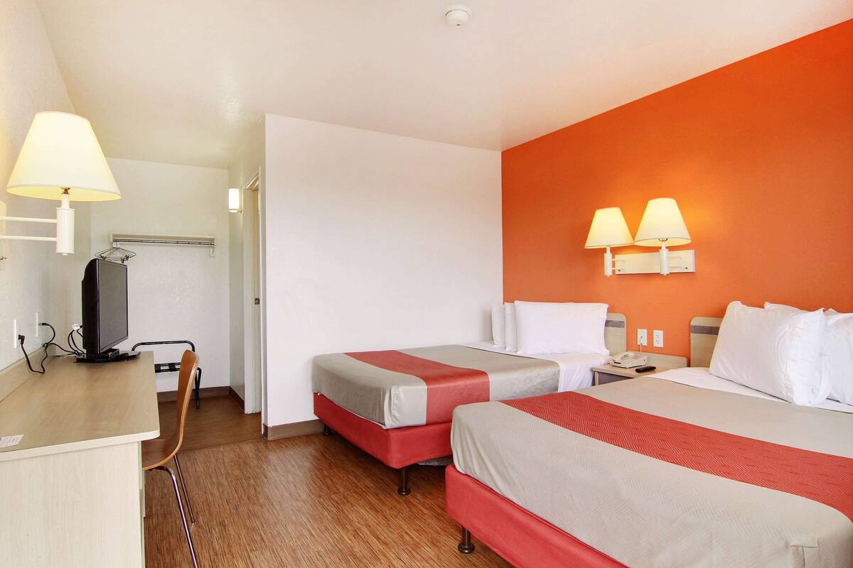 Habitación de hotel con dos camas, un escritorio con computadora y una silla.
