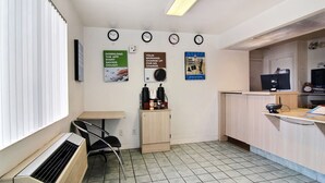 A reception area with a desk, chairs, a clock, and a wall-mounted poster. - Motel 6 Fort Stockton, TX (Fort Stockton)