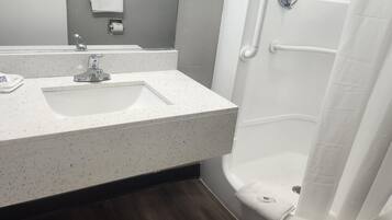 Un baño con un lavabo blanco con motas, un espejo, una toalla y una cortina de ducha.