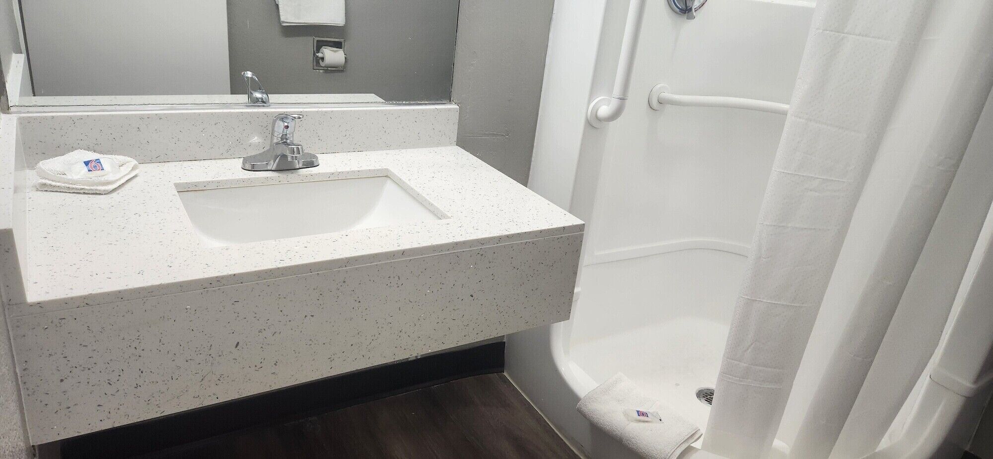 Un baño con un lavabo blanco moteado, un espejo y una cortina de ducha.