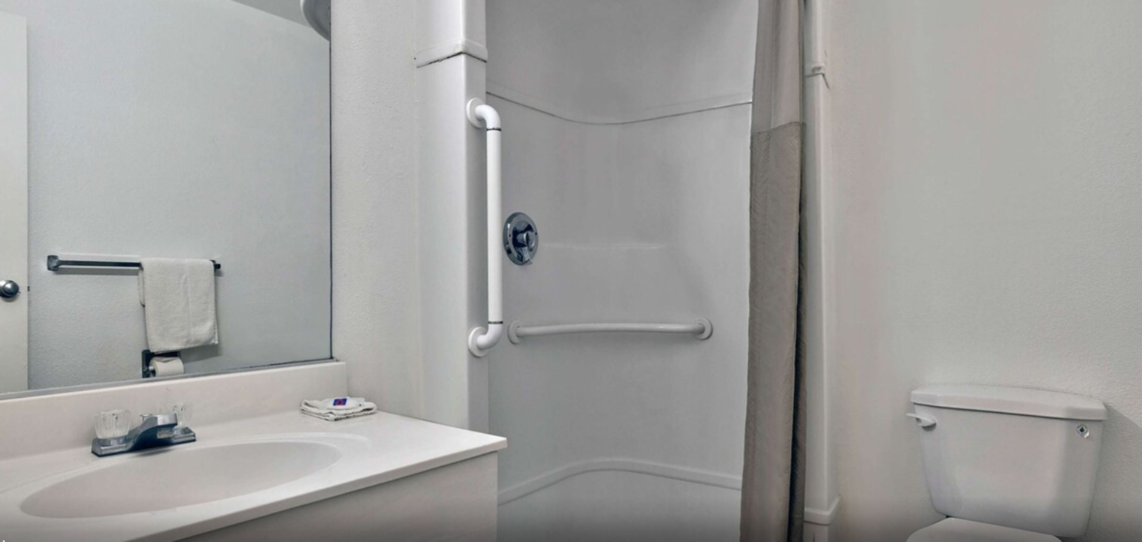 A modern bathroom with a white sink, a mirror, a toilet, and a shower stall.