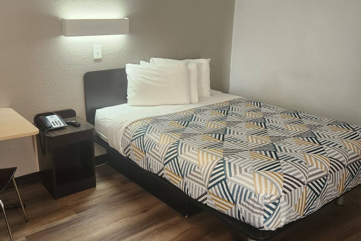 Una habitación de hotel con una cama, un escritorio y una silla.