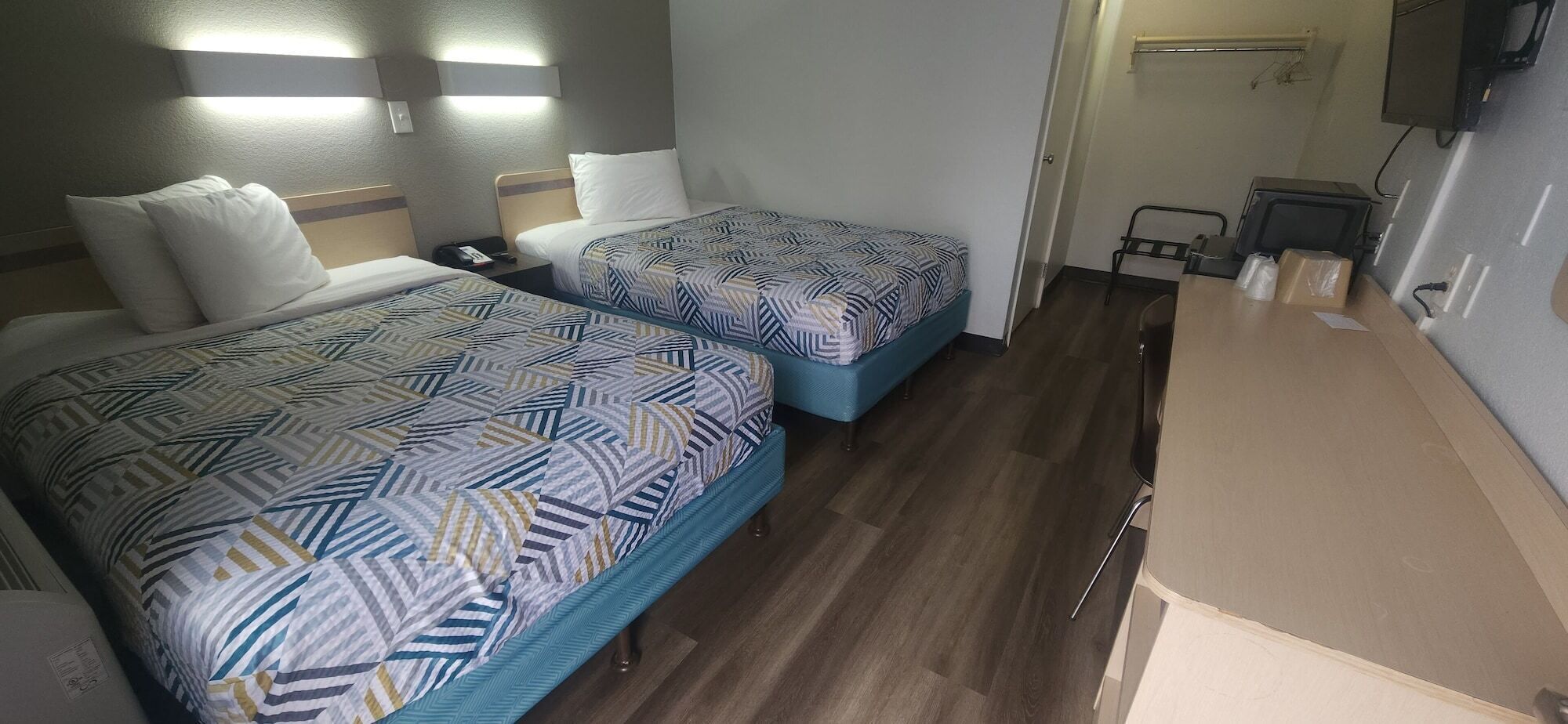 Quarto de hotel com duas camas, uma escrivaninha e uma cadeira.