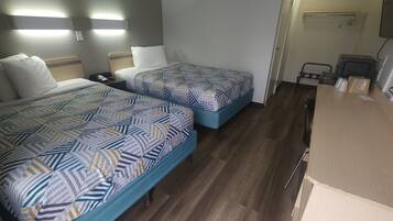 Quarto de hotel com duas camas, uma escrivaninha e uma cadeira.