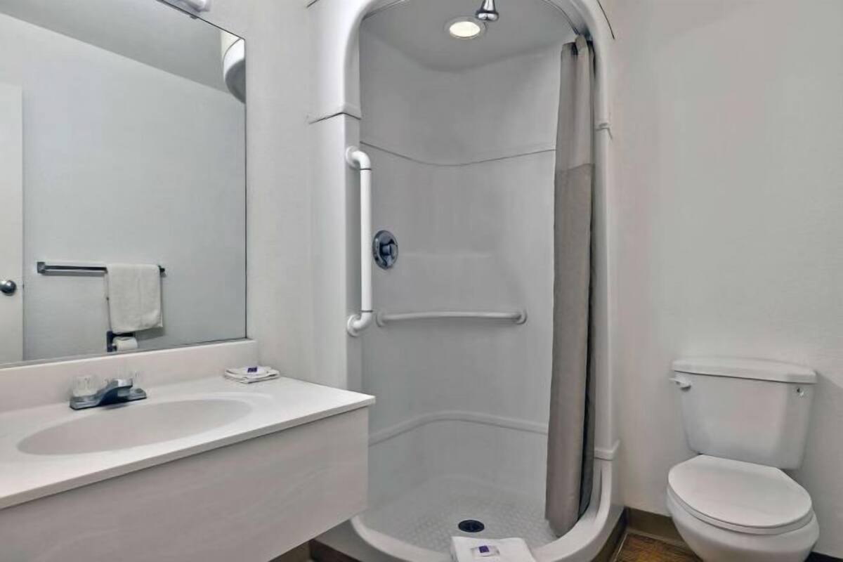 Un baño con ducha, inodoro, lavamanos y espejo.