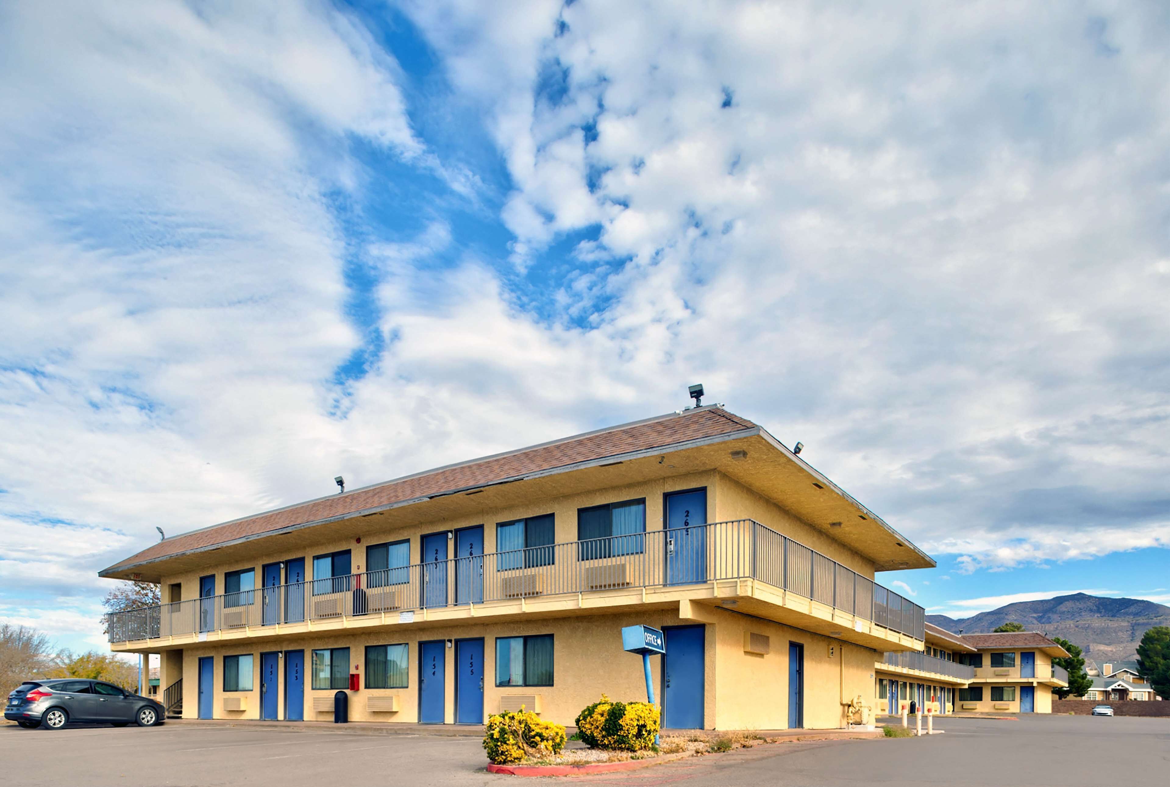 A motel with a two-story structure, multiple balconies, and a parking lot.