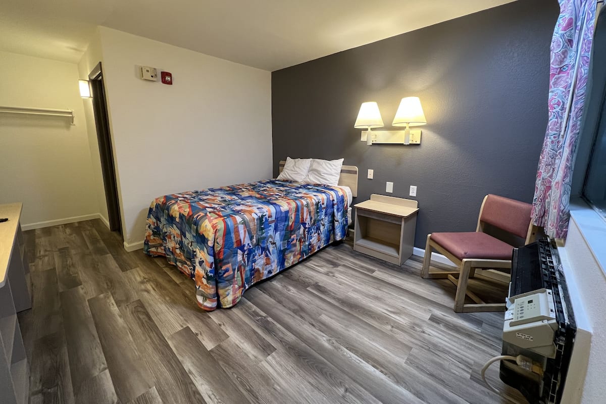 Una camera d'albergo con un letto, comodini, una sedia e una scrivania.