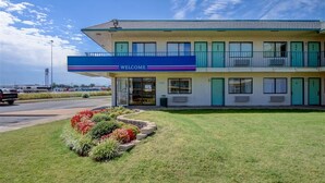Et motel med et 'WELCOME'-skilt, en parkeringsplads og en anlagt have.
