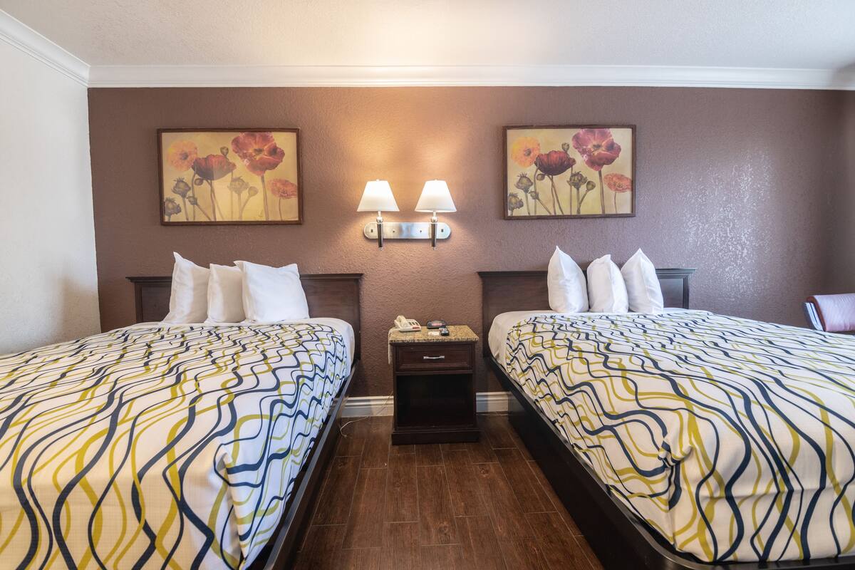 Camera d'albergo con due letti, un comodino e lampade a parete.