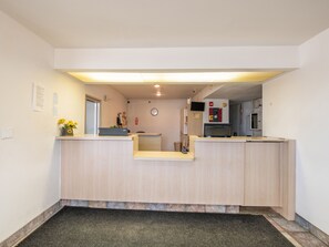 A reception area with a wooden reception desk, a clock on the wall, and a fire extinguisher.