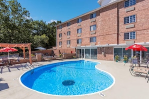 A swimming pool with a brick building in the background.
