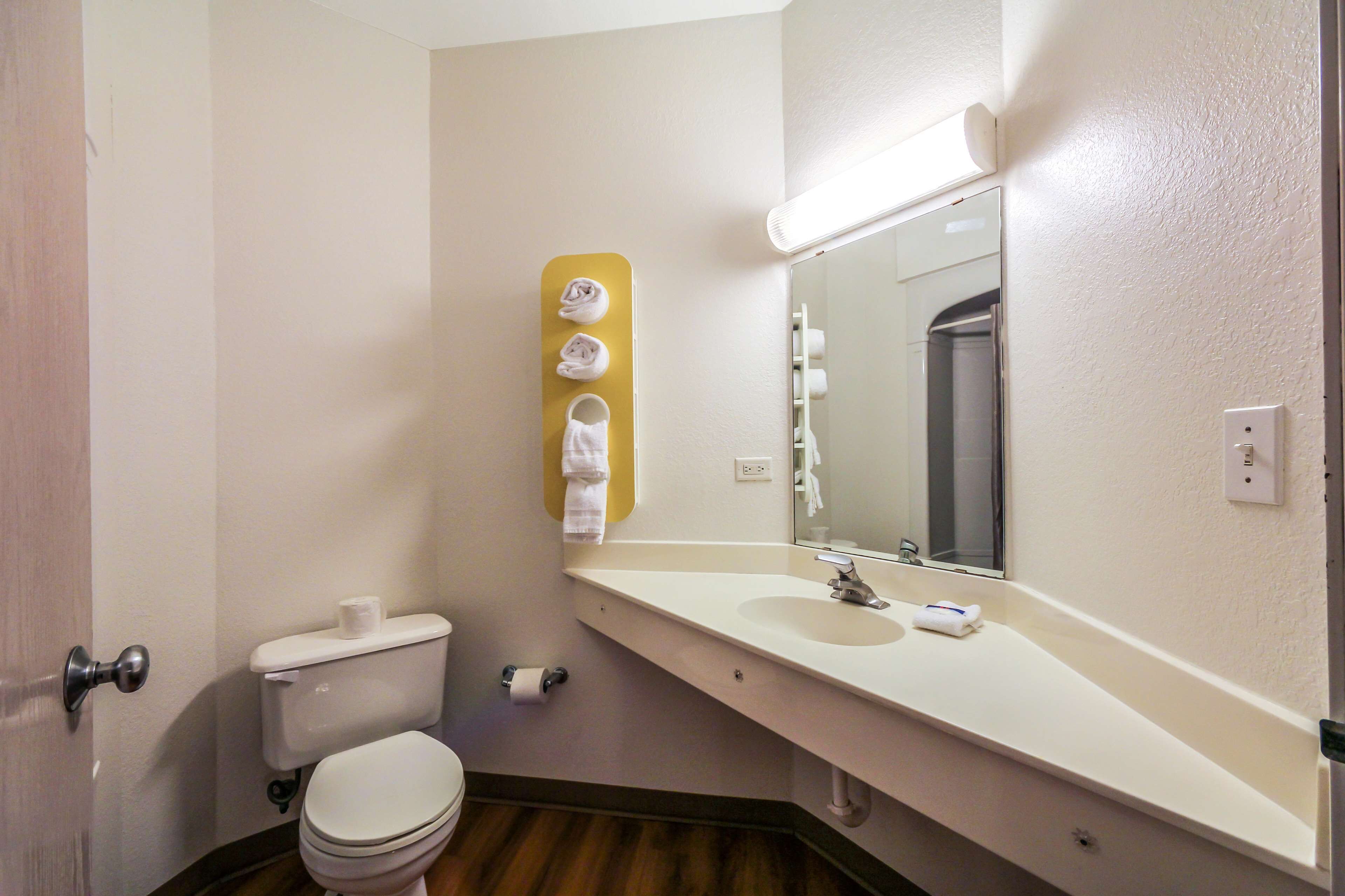 A bathroom with a toilet, sink, mirror, and towel rack.
