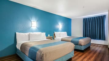 Una habitación de hotel con dos camas, paredes azules, suelo de madera y una ventana con cortinas.