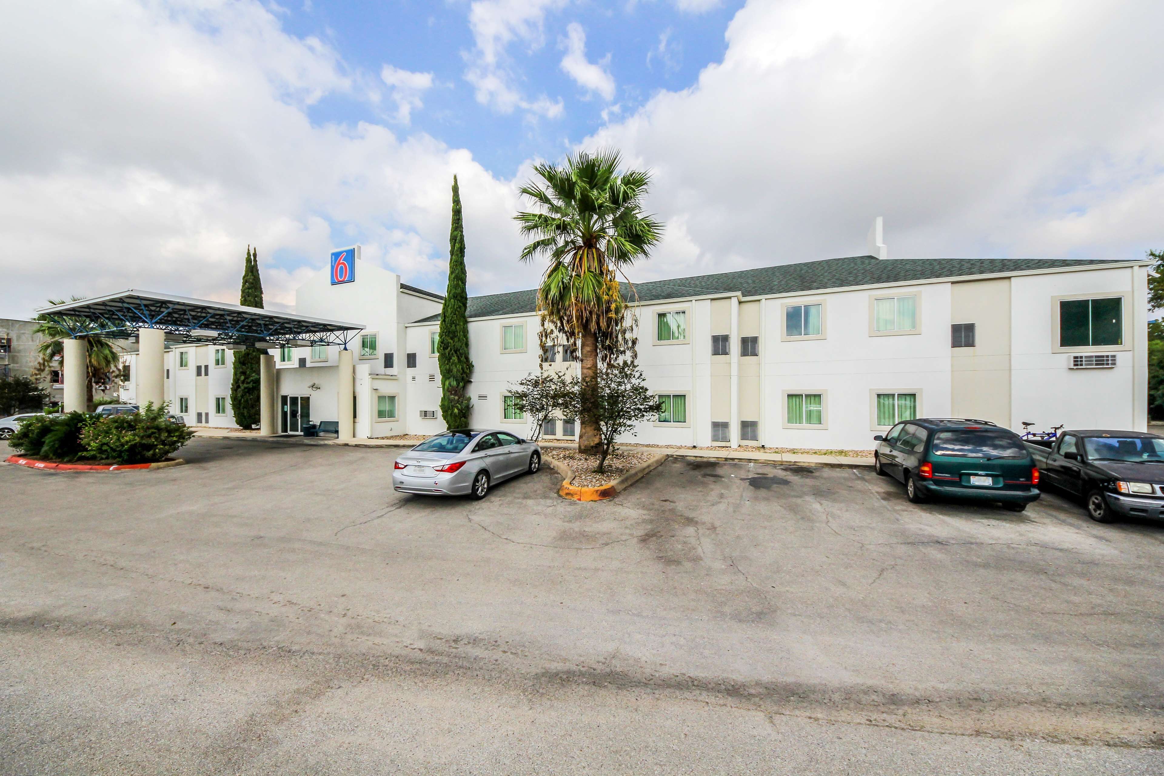 Un hôtel doté d’un parking, d’un espace abrité et d’un palmier.