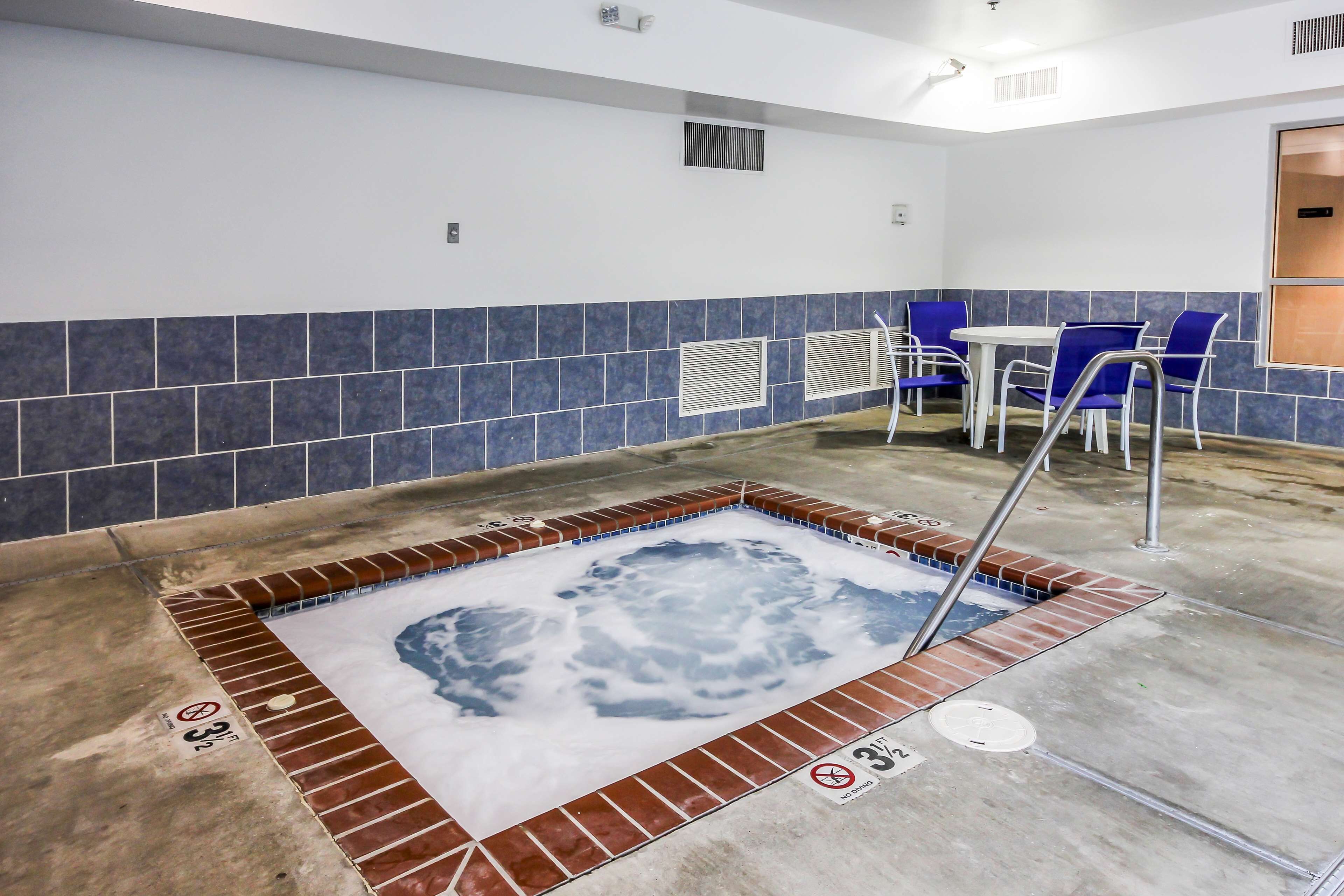 Un espace spa comprenant un jacuzzi, un coin salon et des murs carrelés.