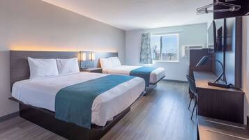 A hotel room with two beds, a desk, a chair, a TV, and a window with a view.