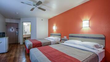 A hotel room with two beds, a ceiling fan, and a kitchenette.