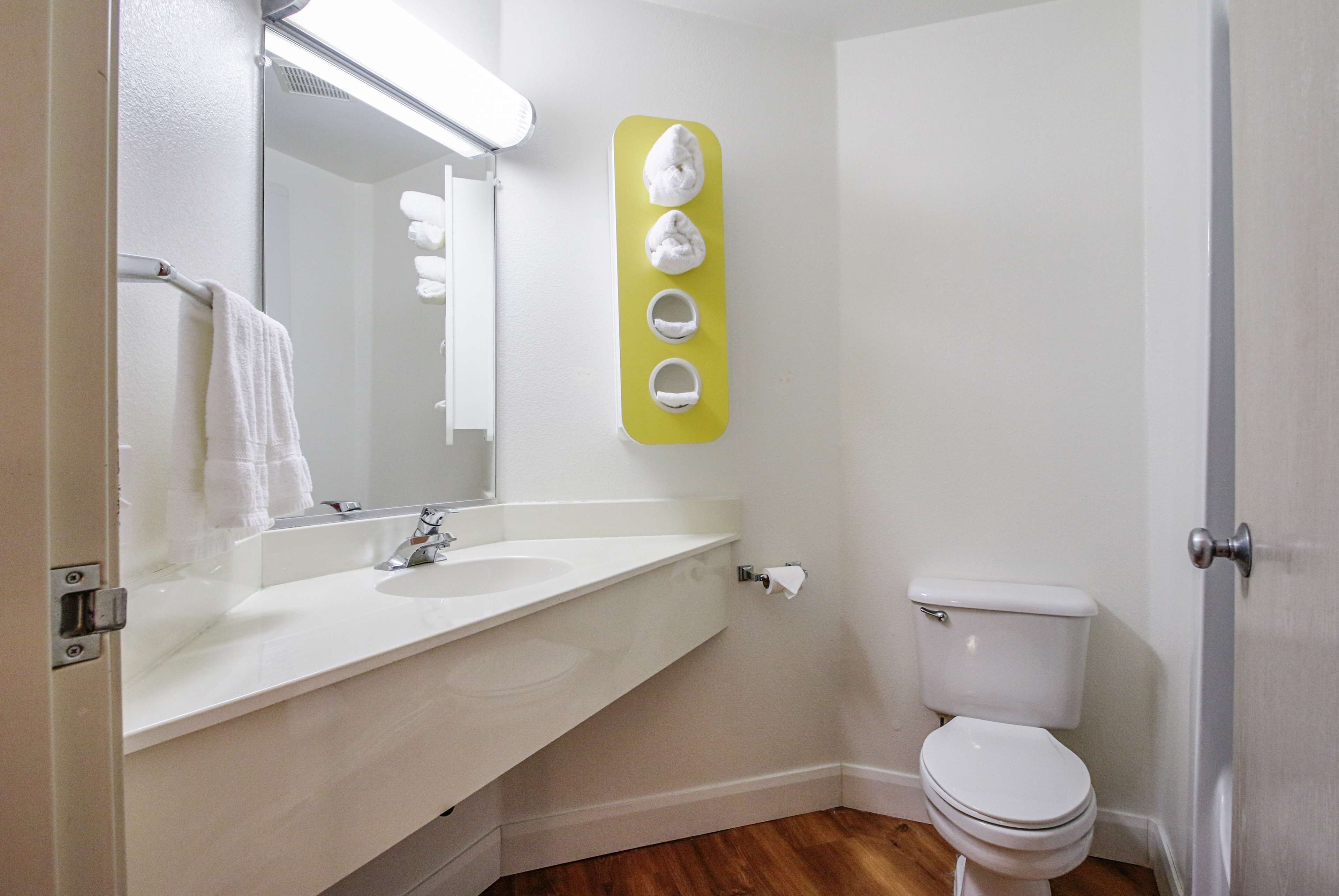 A bathroom with a white sink, mirror, and toilet.