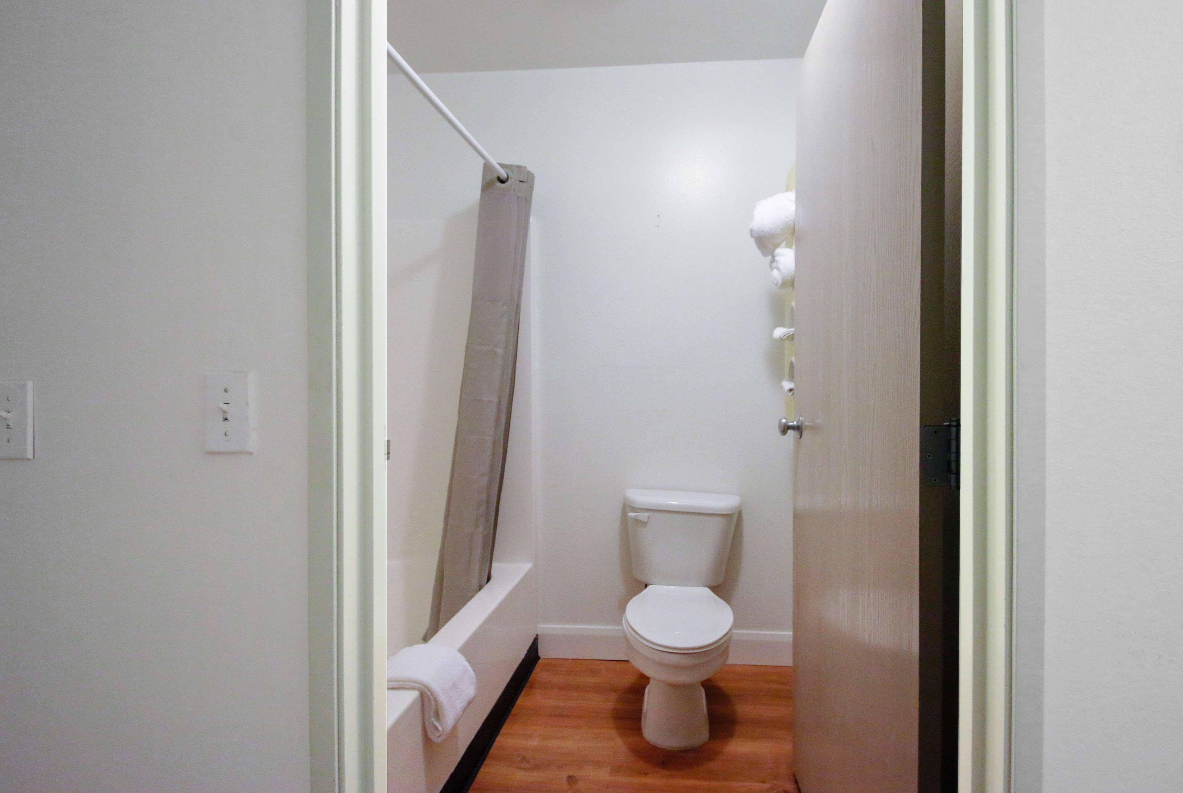 A small, clean bathroom with a white toilet, a bathtub, and a shower curtain.