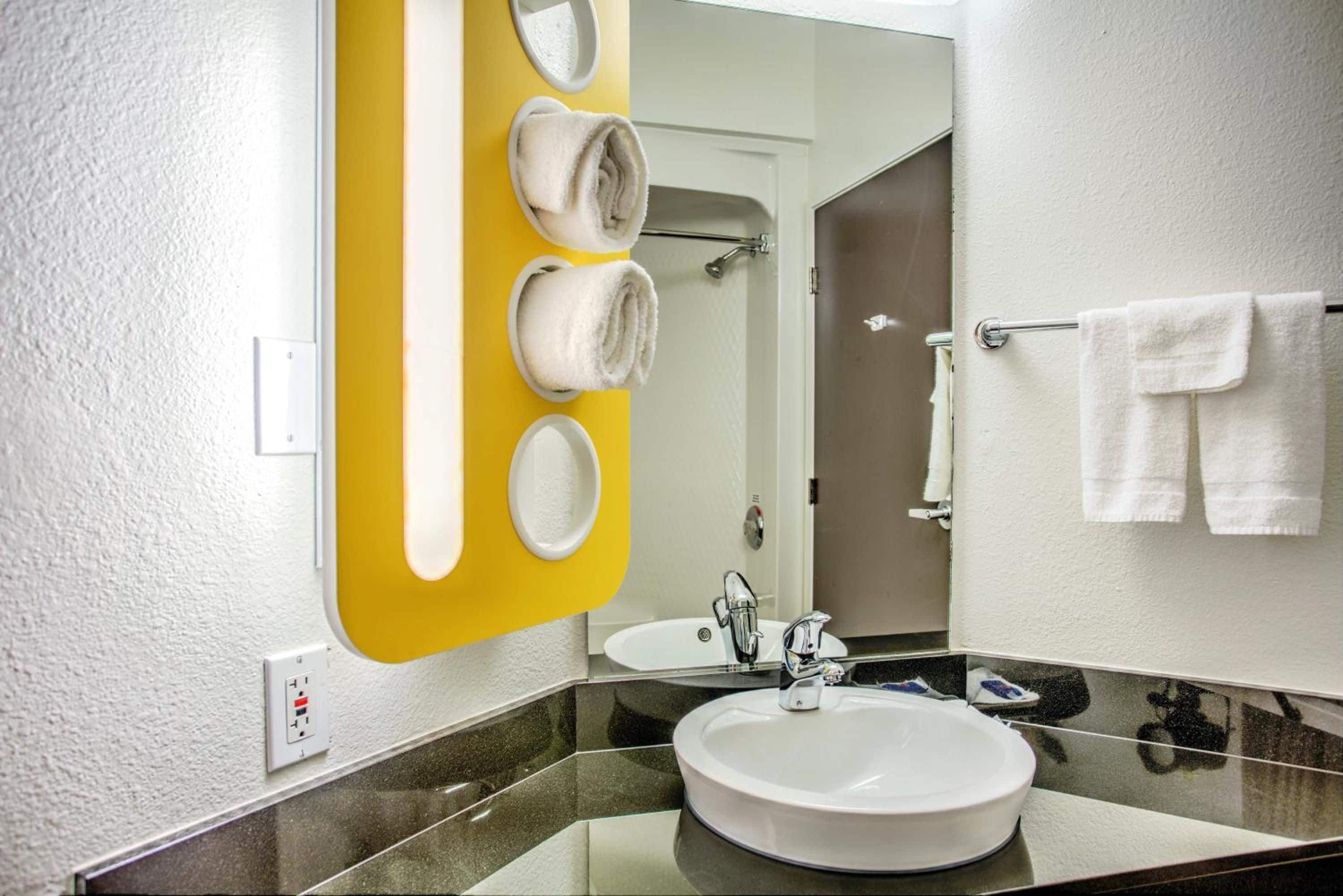 A bathroom with a white sink, a mirror, and a yellow towel rack.