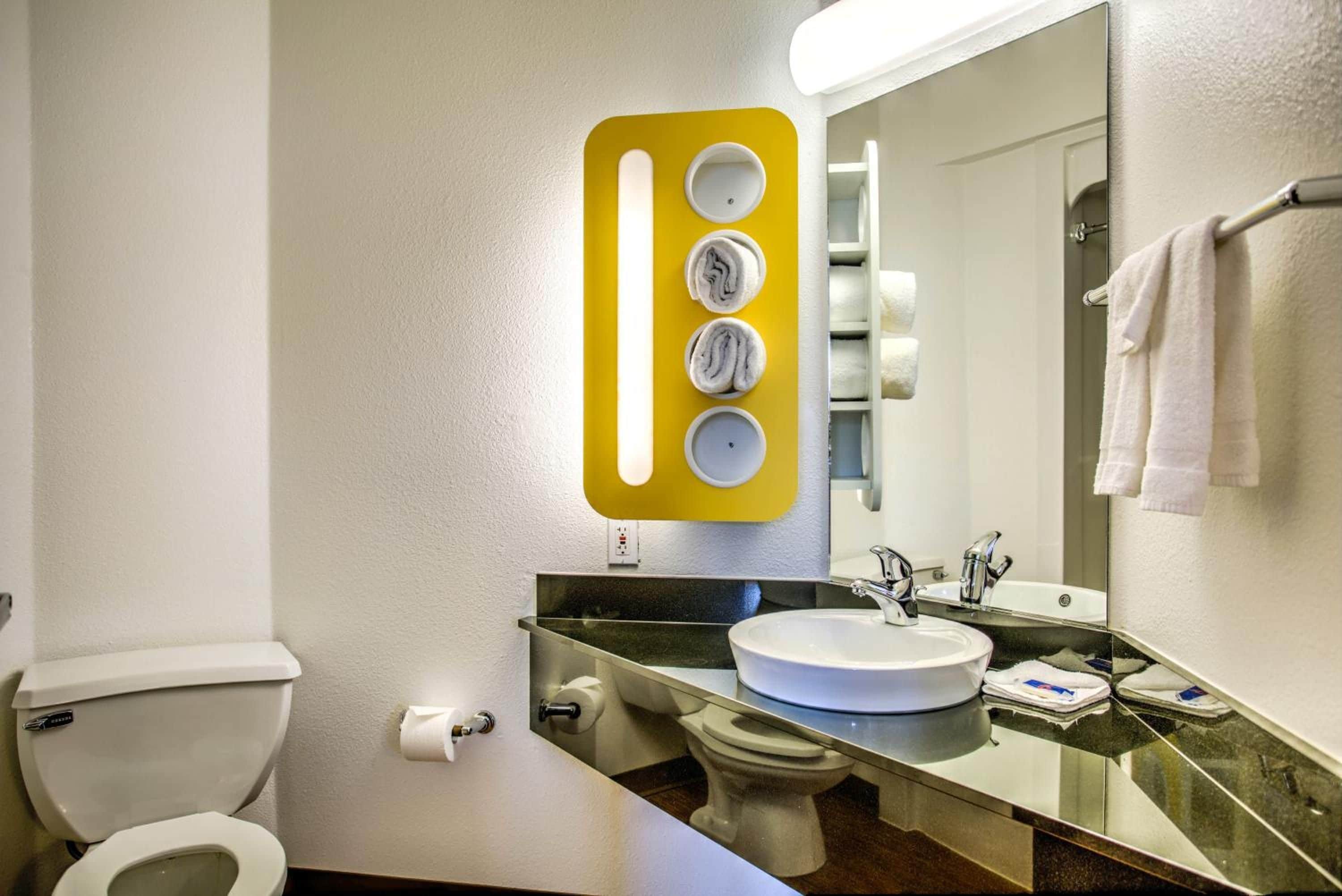 A bathroom with a toilet, sink, and mirror.